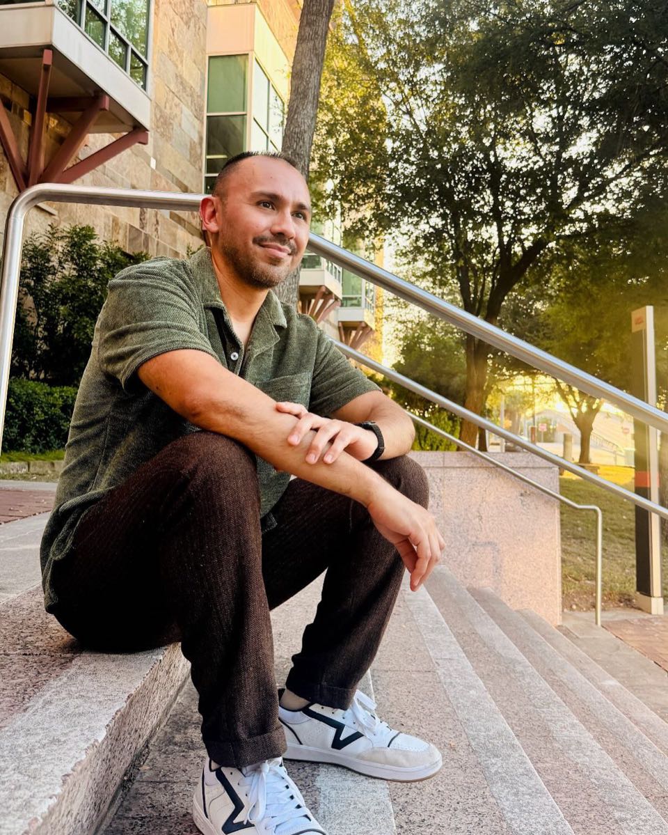 Nick Garcia smiling, sitting on outdoor stone steps in warm evening light